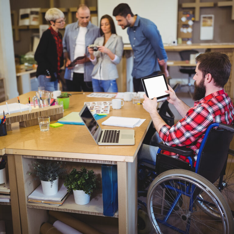 Disabled businessman using digital tablet at desk in creative office